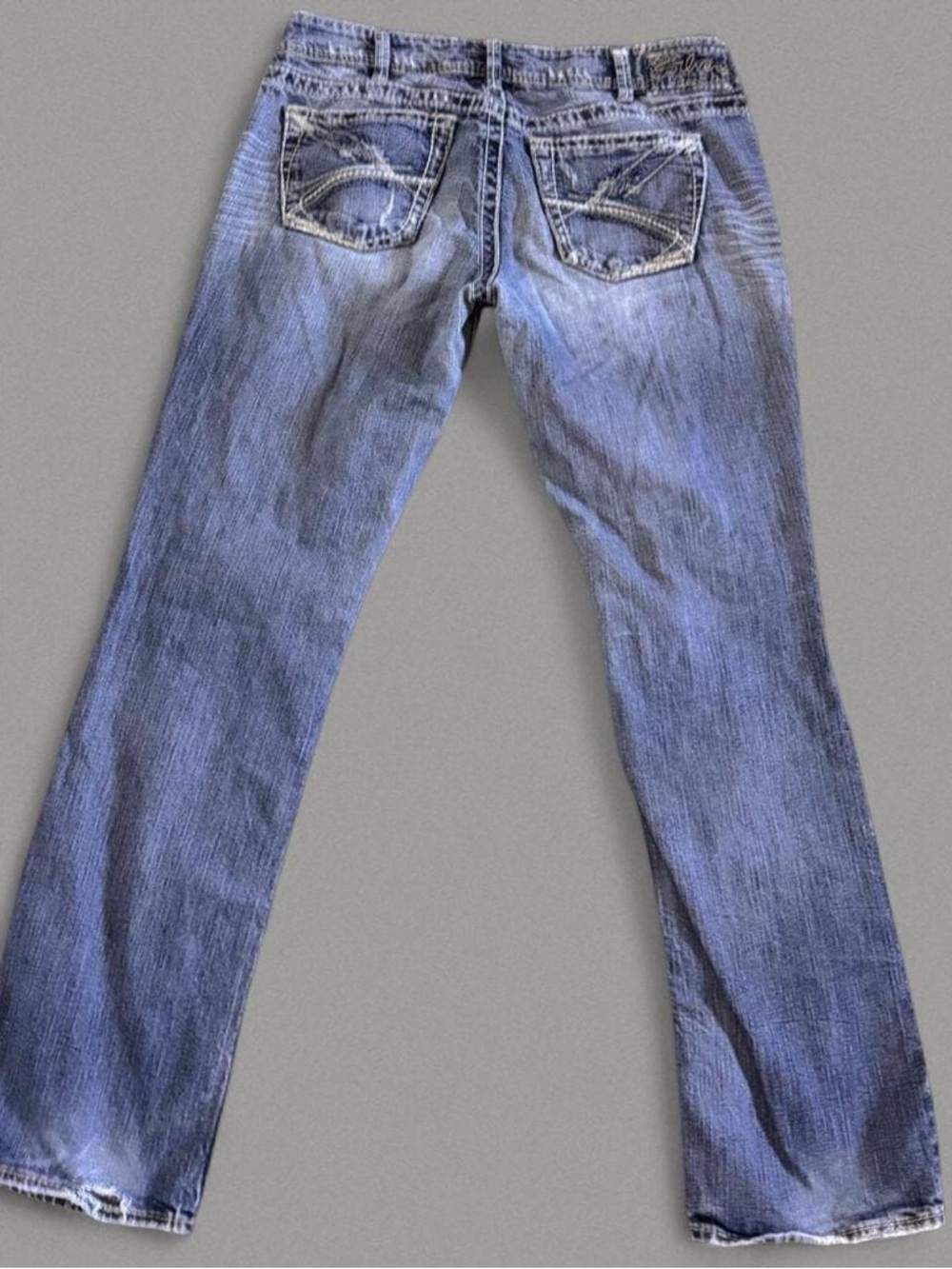 Silver blue jeans with white stitching and distressing